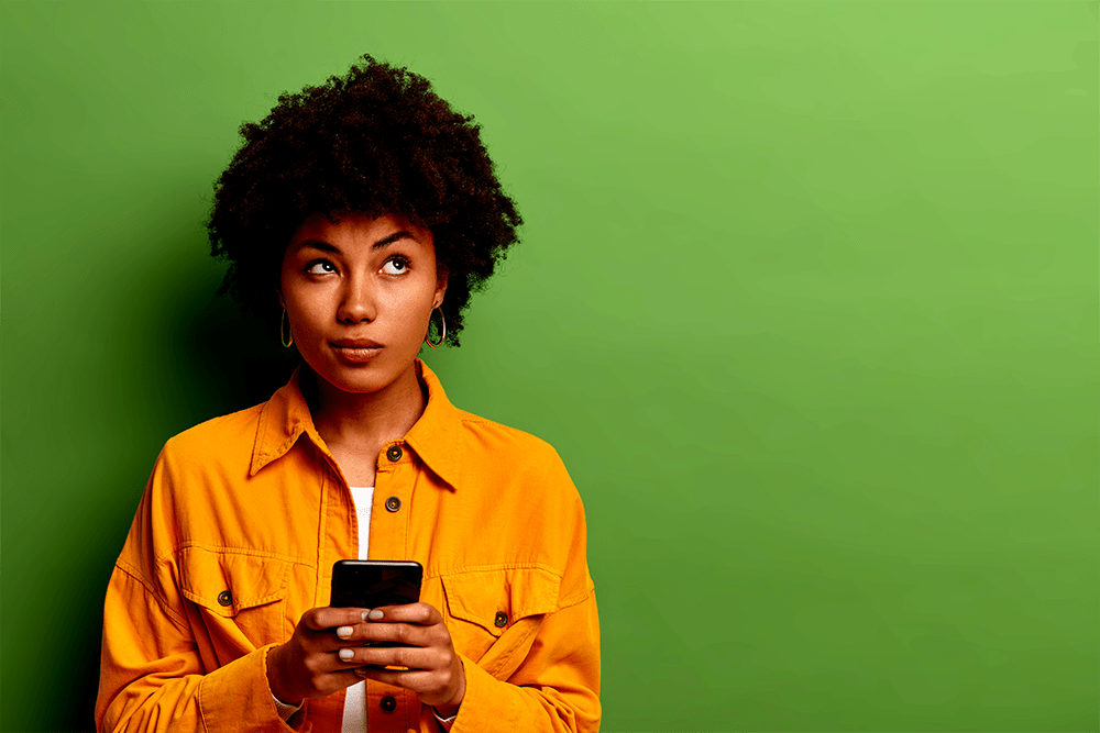 A college student holding a smartphone with a quizzical look on her face.
